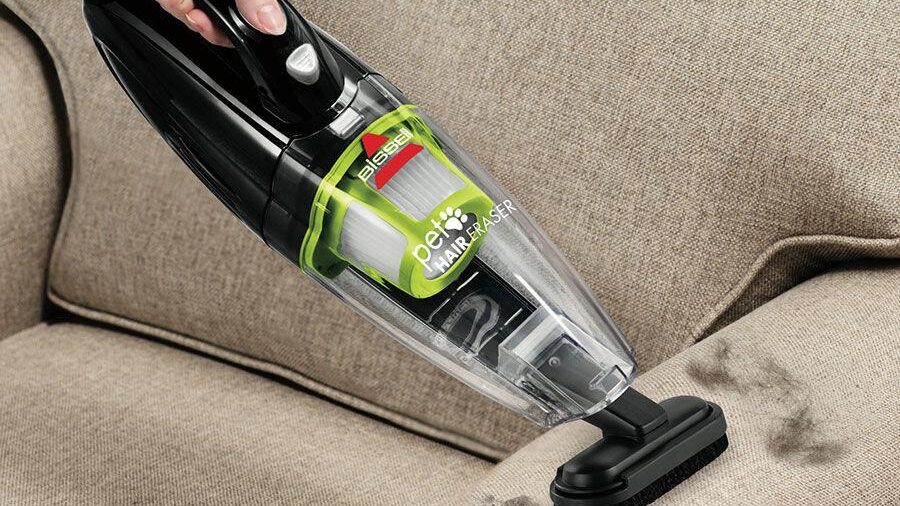 Bissell bezvadu putekļu sūcējs, kas savāc mājdzīvnieku apmatojumu no bēša dīvāna