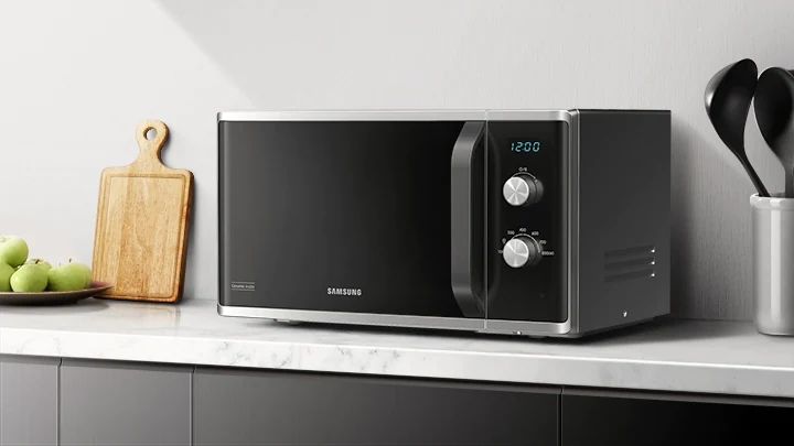 Samsung melna brīvi stāvošā mikroviļņu krāsns uz virtuves skapīša