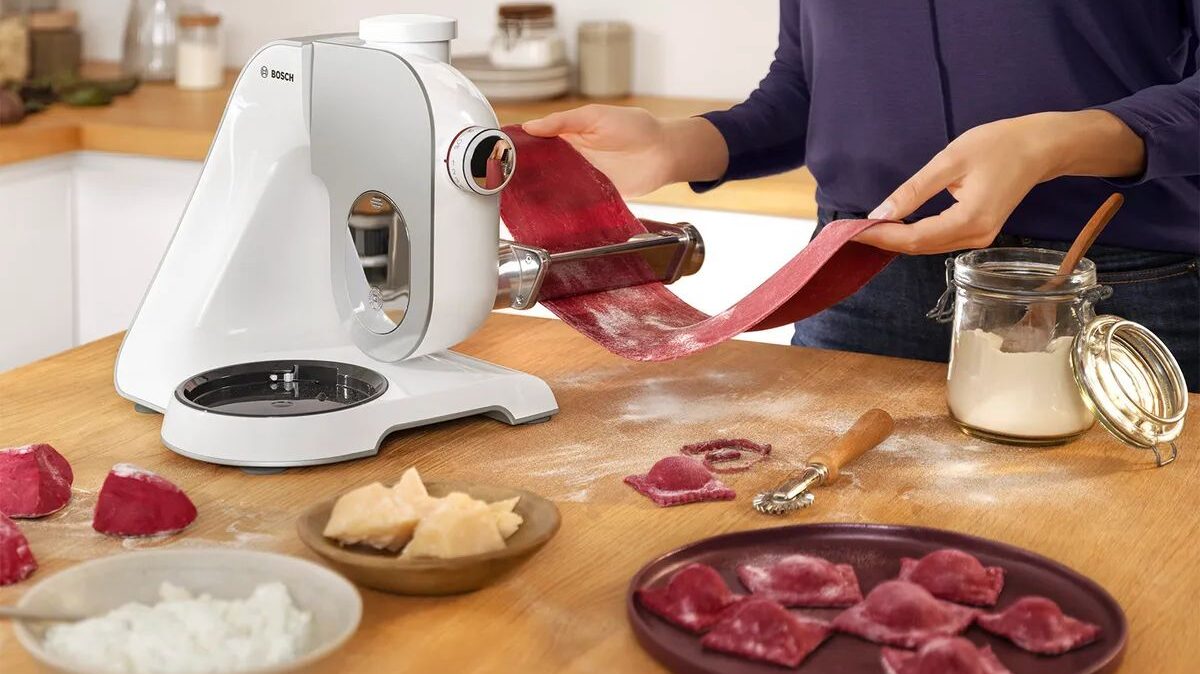 Mazā sadzīves tehnika - Bosch virtuves kombains virtuvē uz ēdiena gatavošanas fona